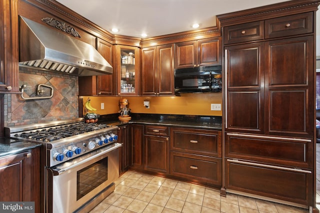 kitchen with light tile patterned flooring, decorative backsplash, stainless steel stove, and wall chimney range hood