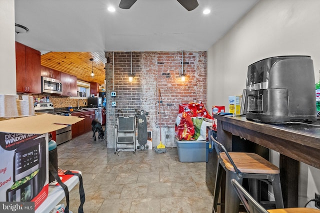 kitchen with appliances with stainless steel finishes, backsplash, brick wall, sink, and pendant lighting