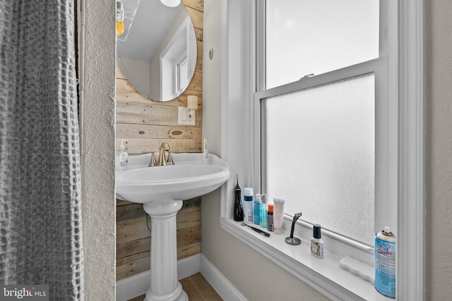 bathroom featuring tile patterned floors and wood walls