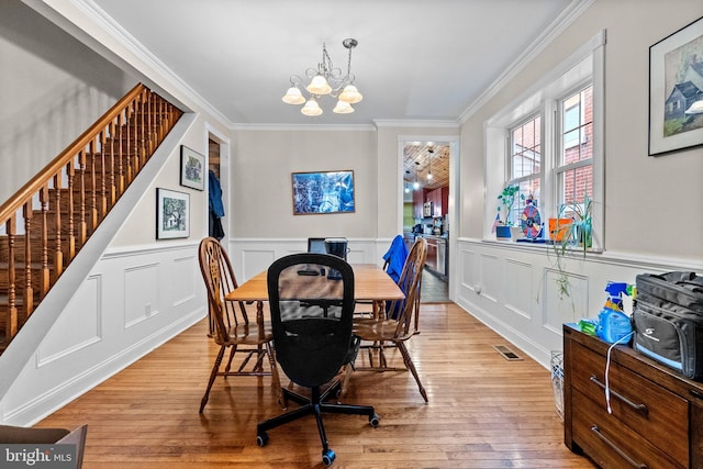 dining space with a chandelier, light wood-type flooring, and ornamental molding