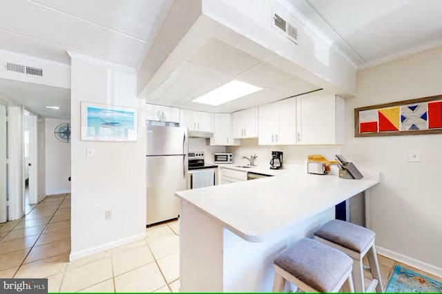 kitchen with white cabinets, a kitchen bar, kitchen peninsula, and appliances with stainless steel finishes