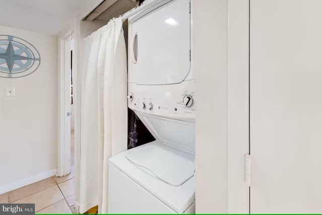 laundry area featuring light tile patterned floors and stacked washer / drying machine