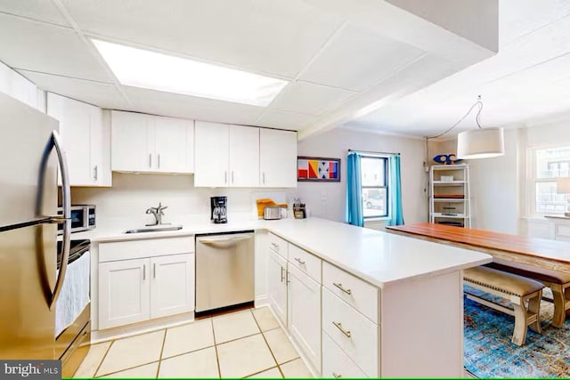 kitchen with pendant lighting, white cabinets, sink, kitchen peninsula, and stainless steel appliances