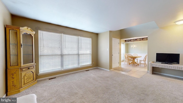 unfurnished living room with a chandelier and light colored carpet