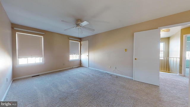 spare room with ceiling fan, light colored carpet, and a wealth of natural light