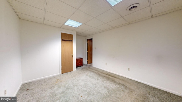 empty room with a drop ceiling and carpet