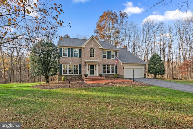 colonial inspired home featuring a garage and a front lawn