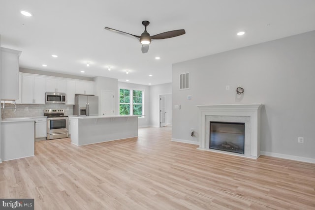 unfurnished living room with ceiling fan and light hardwood / wood-style flooring