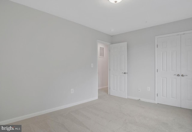 unfurnished bedroom featuring light carpet and a closet