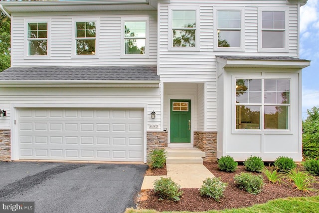 view of front of home with aphalt driveway, stone siding, a shingled roof, and a garage