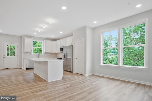 kitchen featuring white cabinetry, plenty of natural light, a kitchen island, and stainless steel appliances