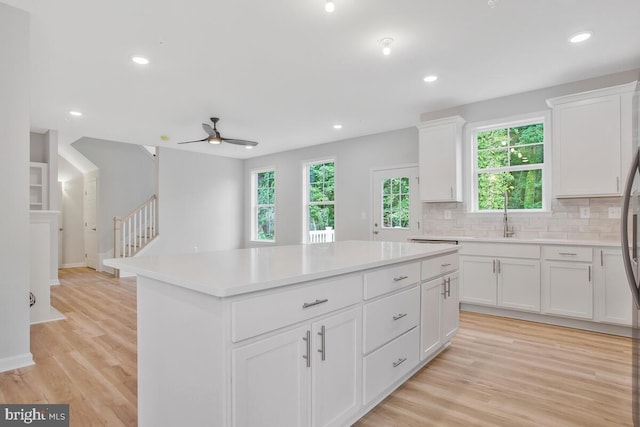 kitchen featuring a center island, white cabinets, a healthy amount of sunlight, and light hardwood / wood-style flooring