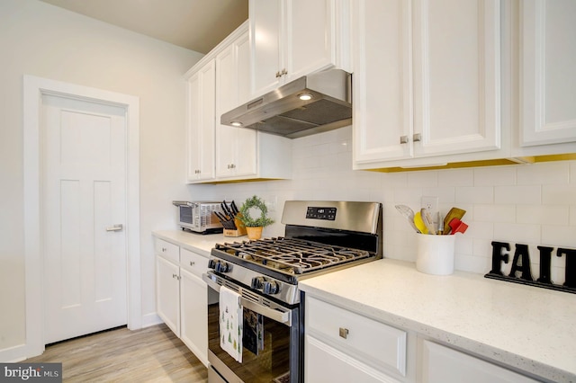 kitchen with decorative backsplash, light stone countertops, light hardwood / wood-style floors, white cabinetry, and gas stove