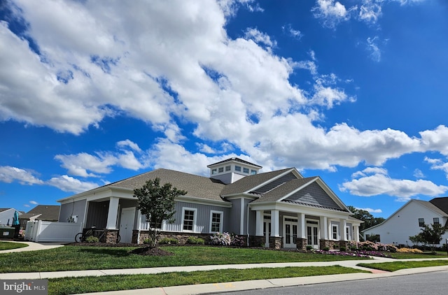craftsman-style home with a front lawn, fence, and stone siding