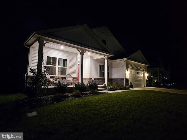 view of front facade with covered porch, a garage, and a lawn