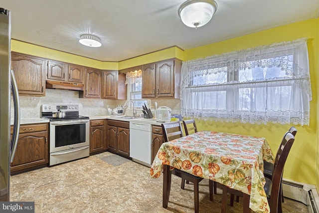 kitchen with sink, decorative backsplash, appliances with stainless steel finishes, a baseboard radiator, and custom range hood