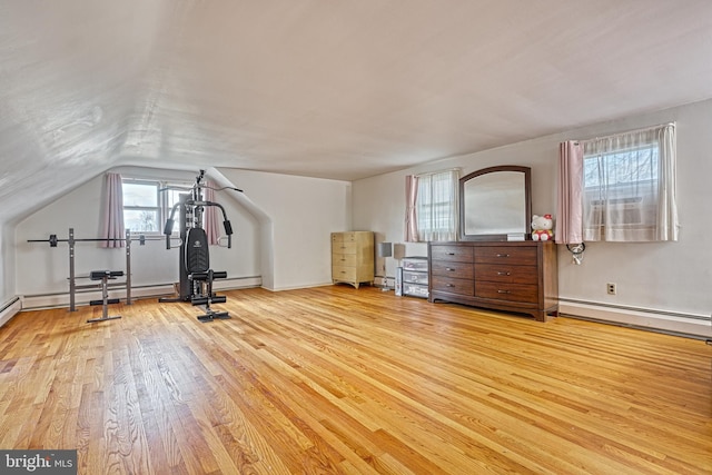 exercise area featuring light hardwood / wood-style floors, vaulted ceiling, and a baseboard heating unit