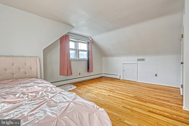 unfurnished bedroom with baseboard heating, lofted ceiling, and hardwood / wood-style flooring