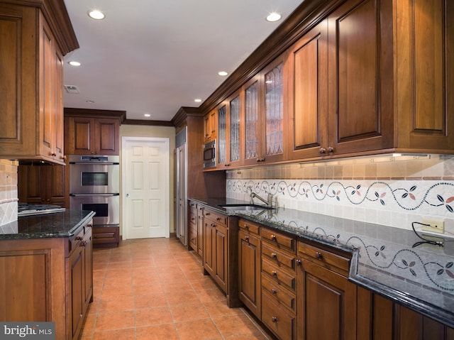 kitchen featuring appliances with stainless steel finishes, backsplash, dark stone countertops, and sink