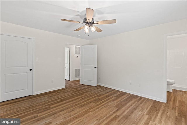 unfurnished bedroom featuring hardwood / wood-style flooring, ceiling fan, and connected bathroom