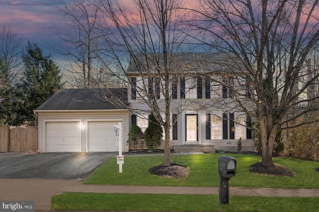 colonial-style house featuring a lawn and a garage