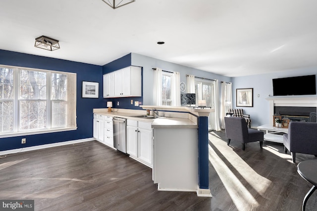 kitchen with kitchen peninsula, white cabinets, stainless steel dishwasher, and dark hardwood / wood-style floors