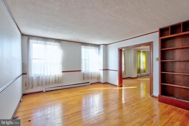 empty room with a textured ceiling, a baseboard radiator, crown molding, and light hardwood / wood-style floors