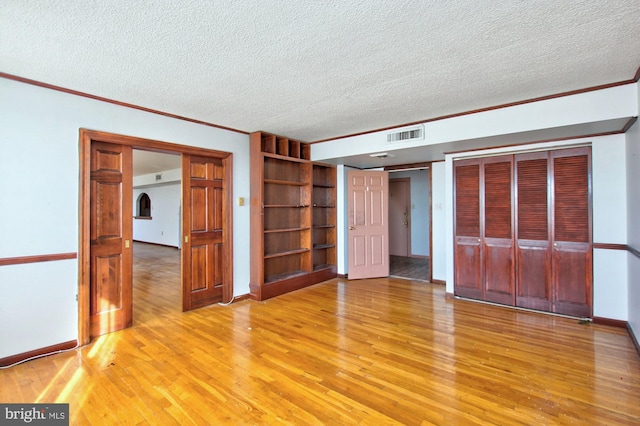 interior space featuring crown molding, a textured ceiling, and light hardwood / wood-style flooring