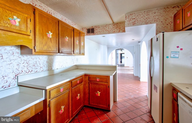 kitchen featuring a textured ceiling, kitchen peninsula, light tile patterned floors, and white appliances