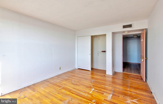 unfurnished bedroom with a textured ceiling, light hardwood / wood-style flooring, and a closet