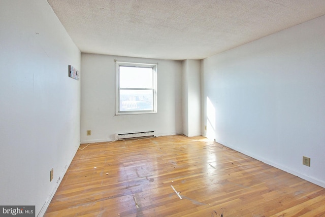 spare room featuring baseboard heating, light hardwood / wood-style floors, and a textured ceiling