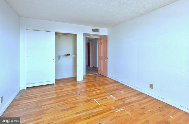 unfurnished bedroom with wood-type flooring, a textured ceiling, and a closet