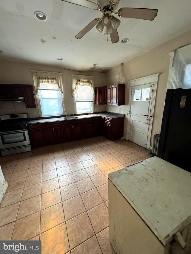 kitchen featuring gas range, ceiling fan, sink, light tile patterned floors, and exhaust hood