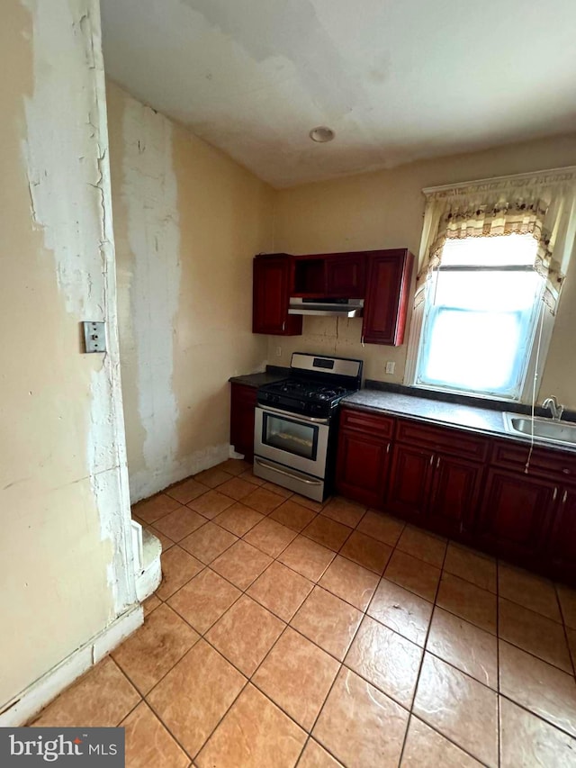 kitchen with light tile patterned floors, gas stove, and sink