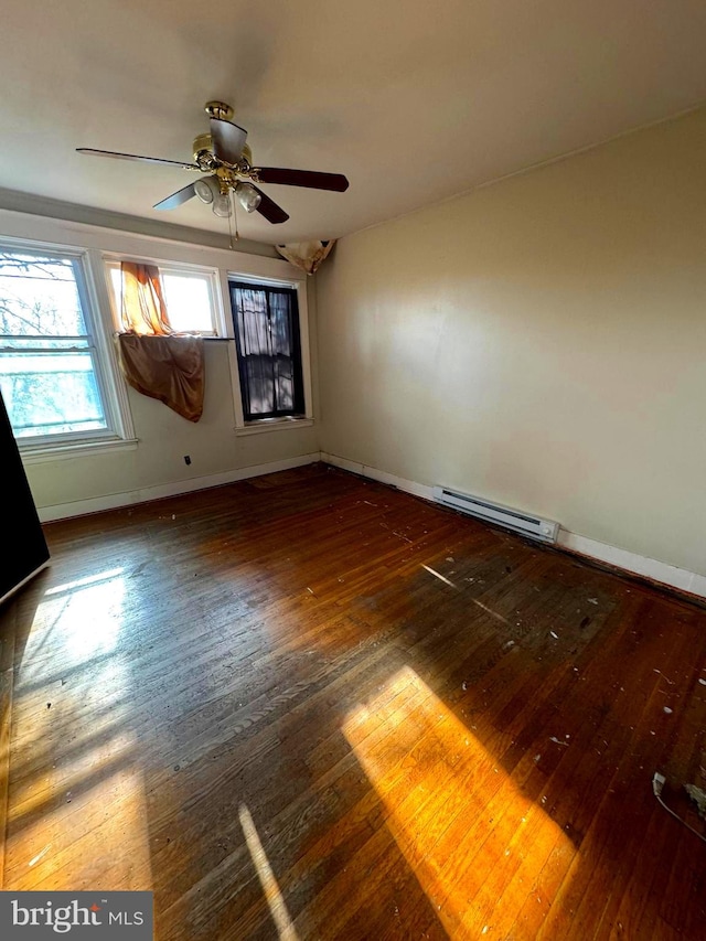 empty room featuring ceiling fan, baseboard heating, and dark wood-type flooring