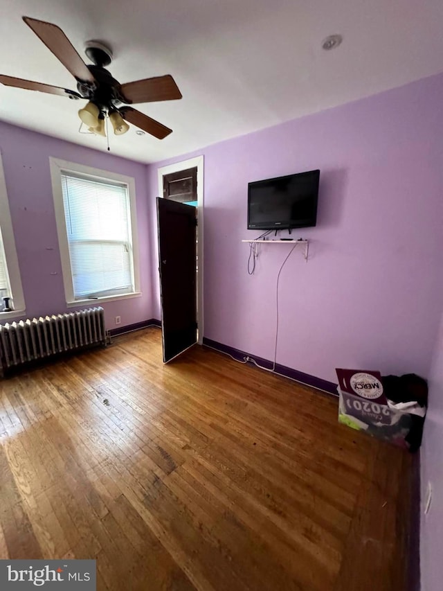 unfurnished bedroom featuring hardwood / wood-style flooring, ceiling fan, and radiator heating unit