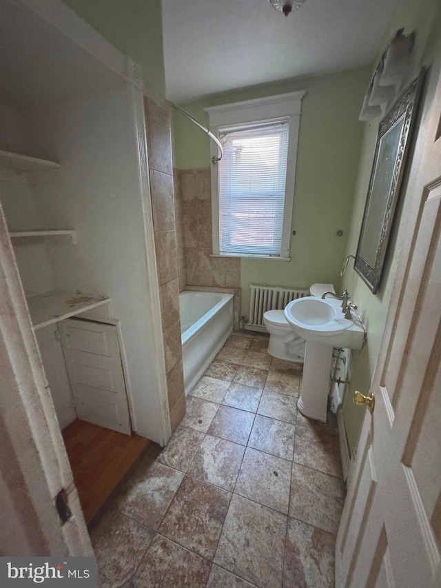 bathroom with toilet, radiator heating unit, and tiled shower / bath