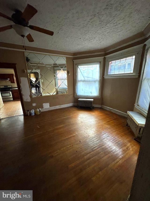 interior space with hardwood / wood-style floors, crown molding, ceiling fan, a textured ceiling, and radiator heating unit