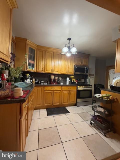 kitchen featuring light tile patterned floors, pendant lighting, stainless steel appliances, and a notable chandelier