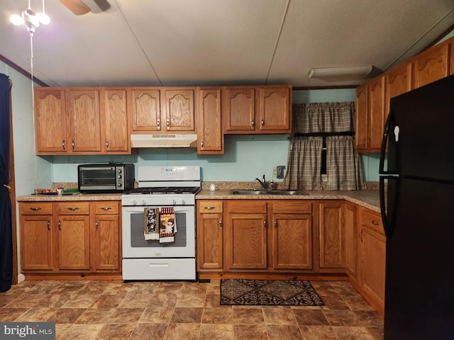 kitchen with white gas range, ceiling fan, black refrigerator, and sink