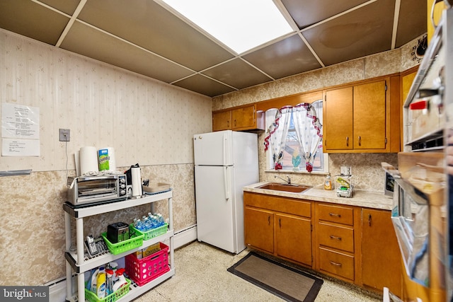 kitchen featuring a paneled ceiling, stainless steel oven, sink, and white fridge