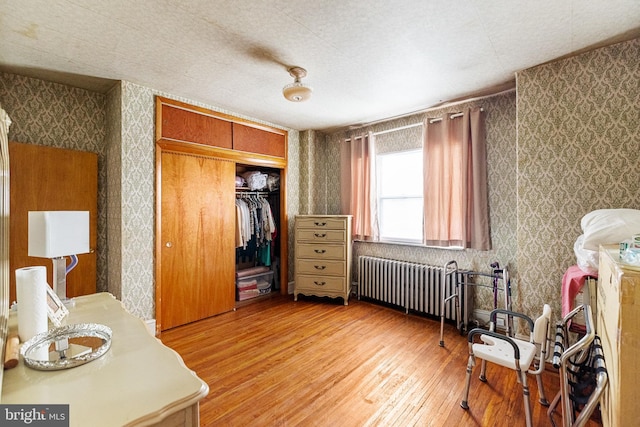 bedroom featuring a closet, radiator, and hardwood / wood-style flooring