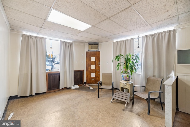 sitting room with a paneled ceiling, radiator heating unit, and a wall mounted AC