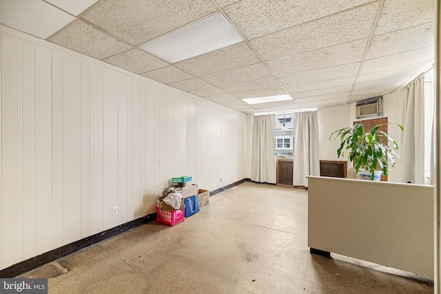 interior space featuring a paneled ceiling, a wall mounted AC, and wood walls