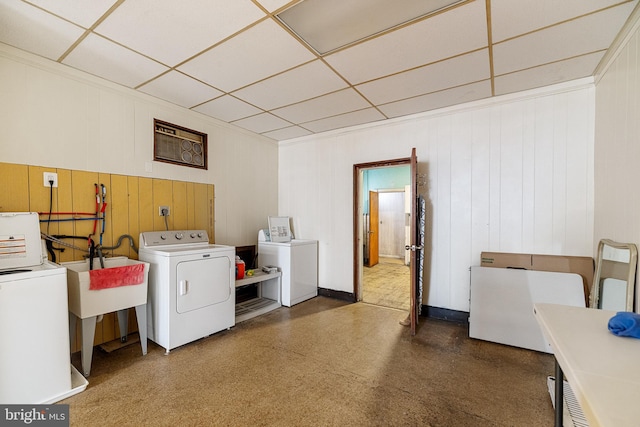 washroom featuring independent washer and dryer, wooden walls, and sink