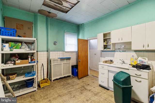 kitchen featuring white cabinetry, tile walls, and sink