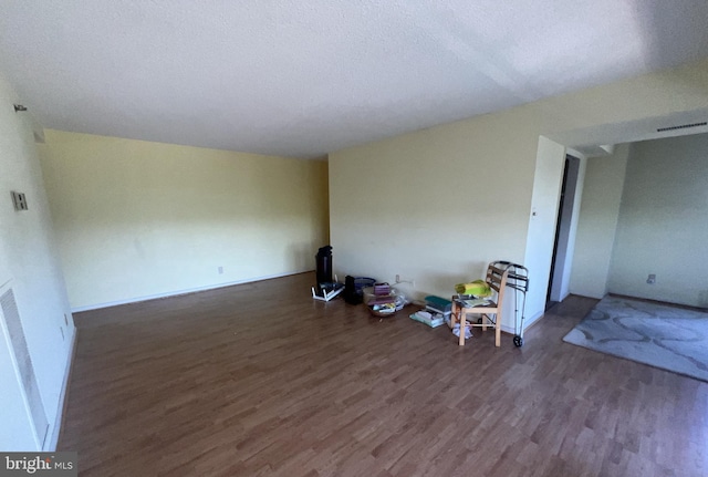 spare room featuring a textured ceiling and dark hardwood / wood-style floors