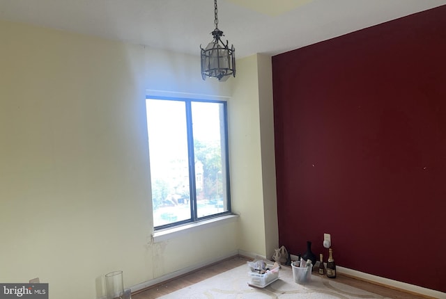 unfurnished room with a chandelier and wood-type flooring