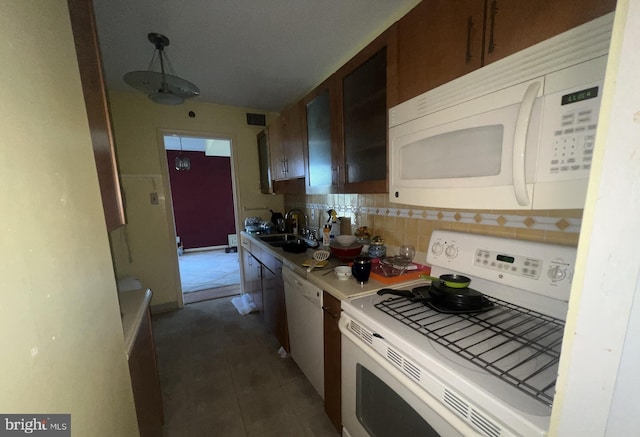 kitchen with tasteful backsplash, white appliances, sink, decorative light fixtures, and dark tile patterned flooring