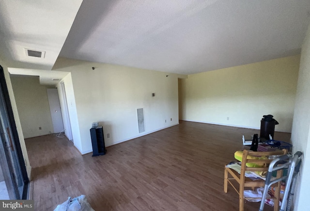 unfurnished living room with a textured ceiling and dark hardwood / wood-style flooring